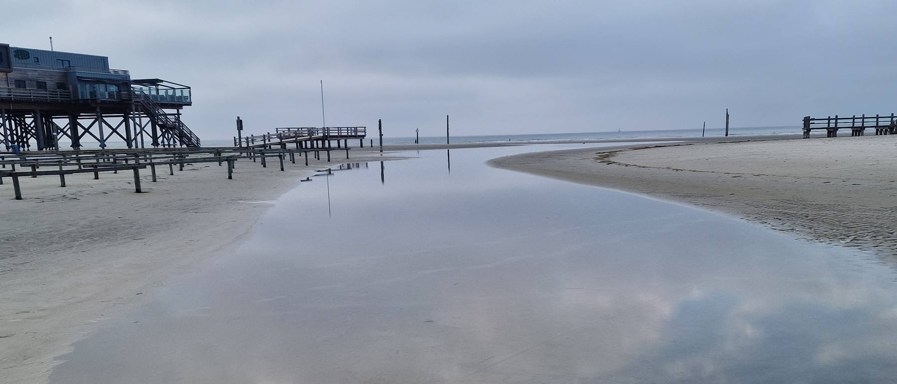 Die Pfahlbauten von St. Peter-Ording spiegeln sich im Priel